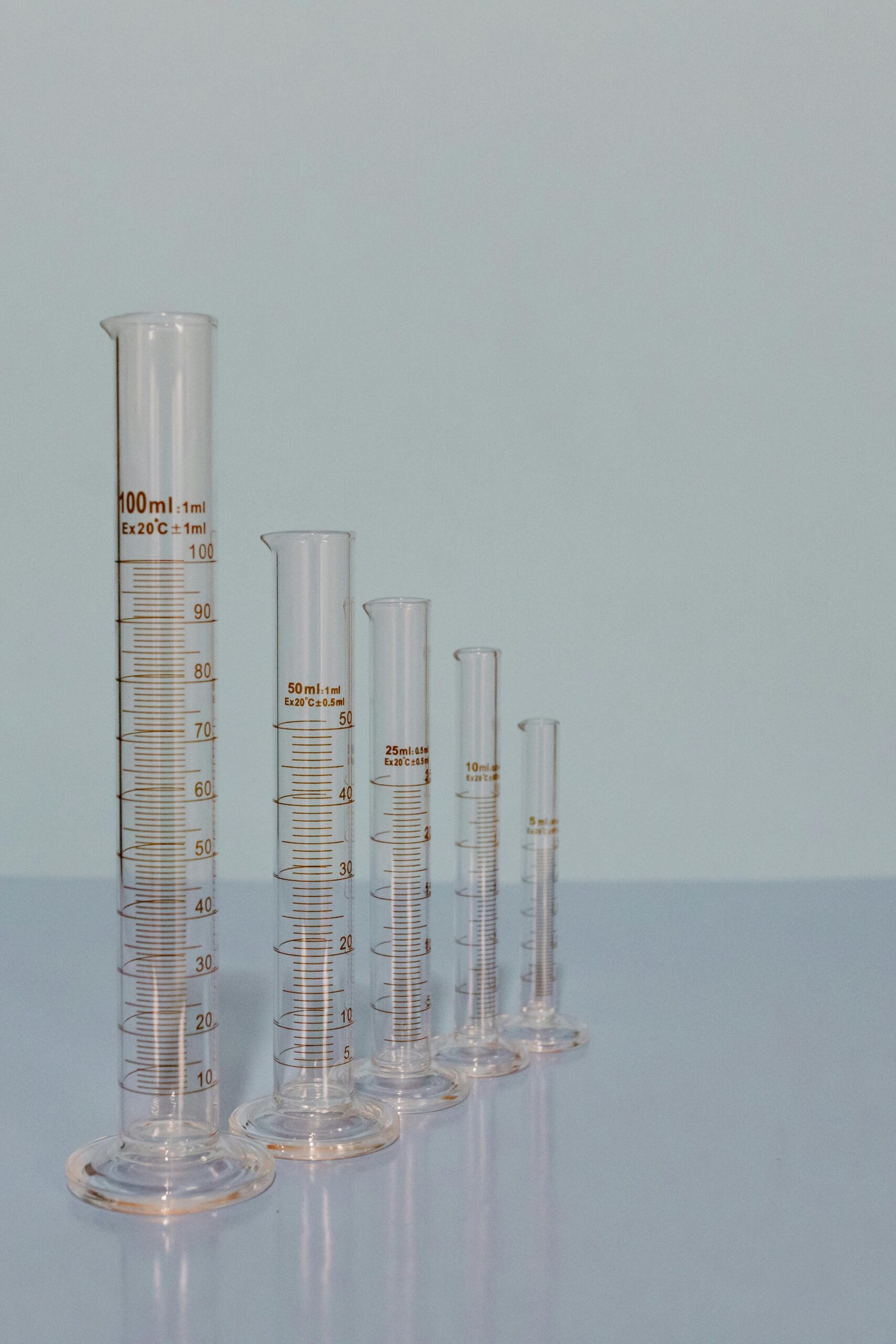 Five graduated cylinders of different sizes lined up on a laboratory surface.