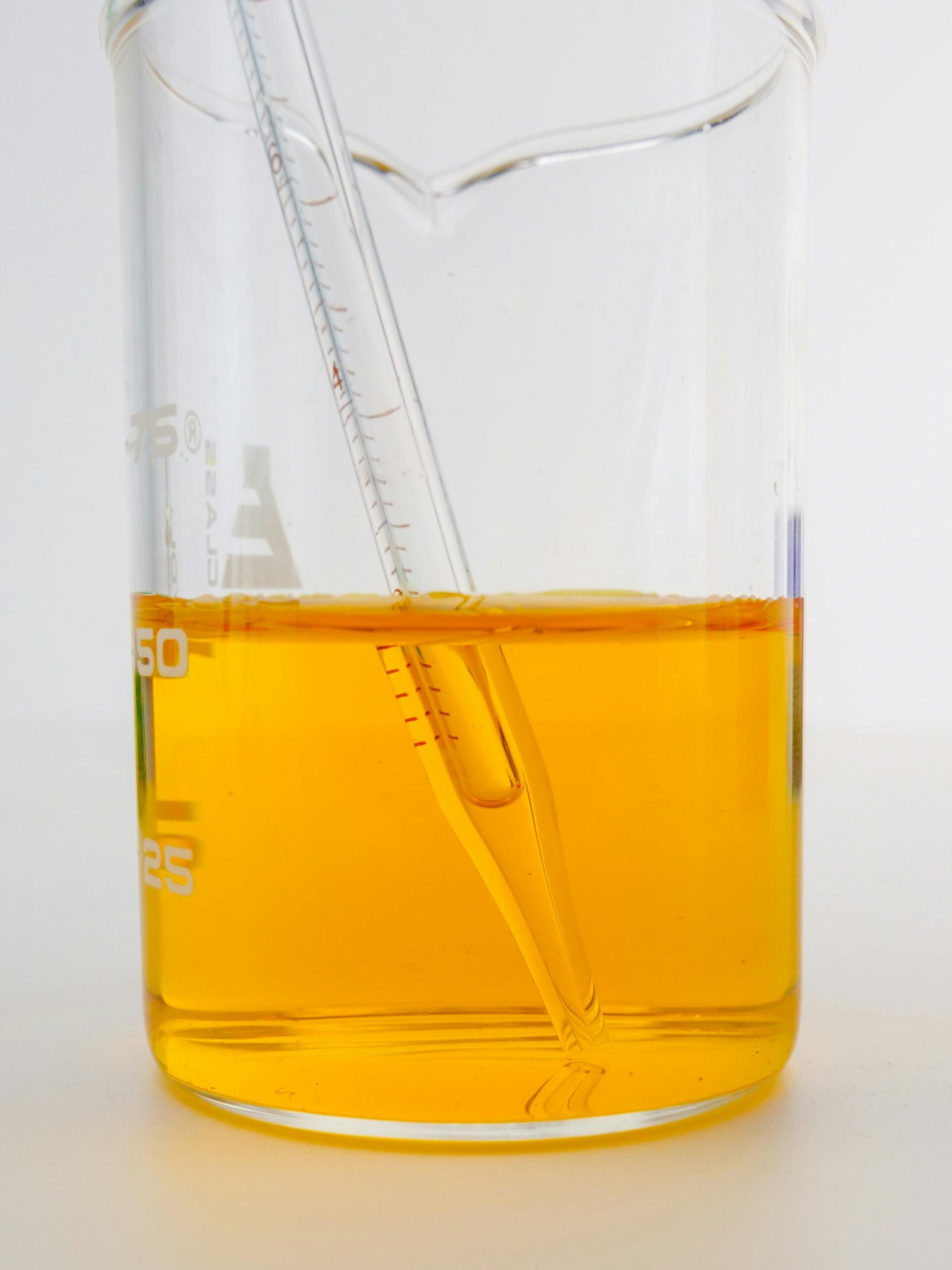 A detailed view of a yellow liquid in a laboratory beaker with a pipette, perfect for science themes.
