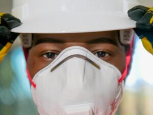 Focused close-up of a worker wearing a hard hat and N95 mask, highlighting safety.