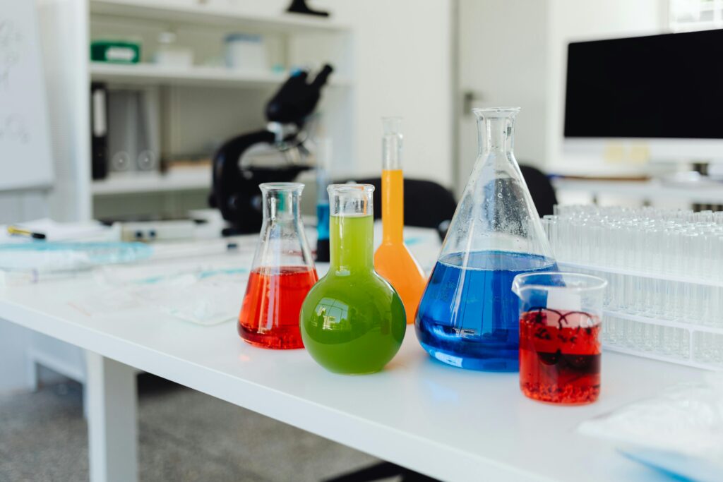 Bright, colorful chemicals in flasks and beakers on a lab table indicating a chemistry experiment in progress.
