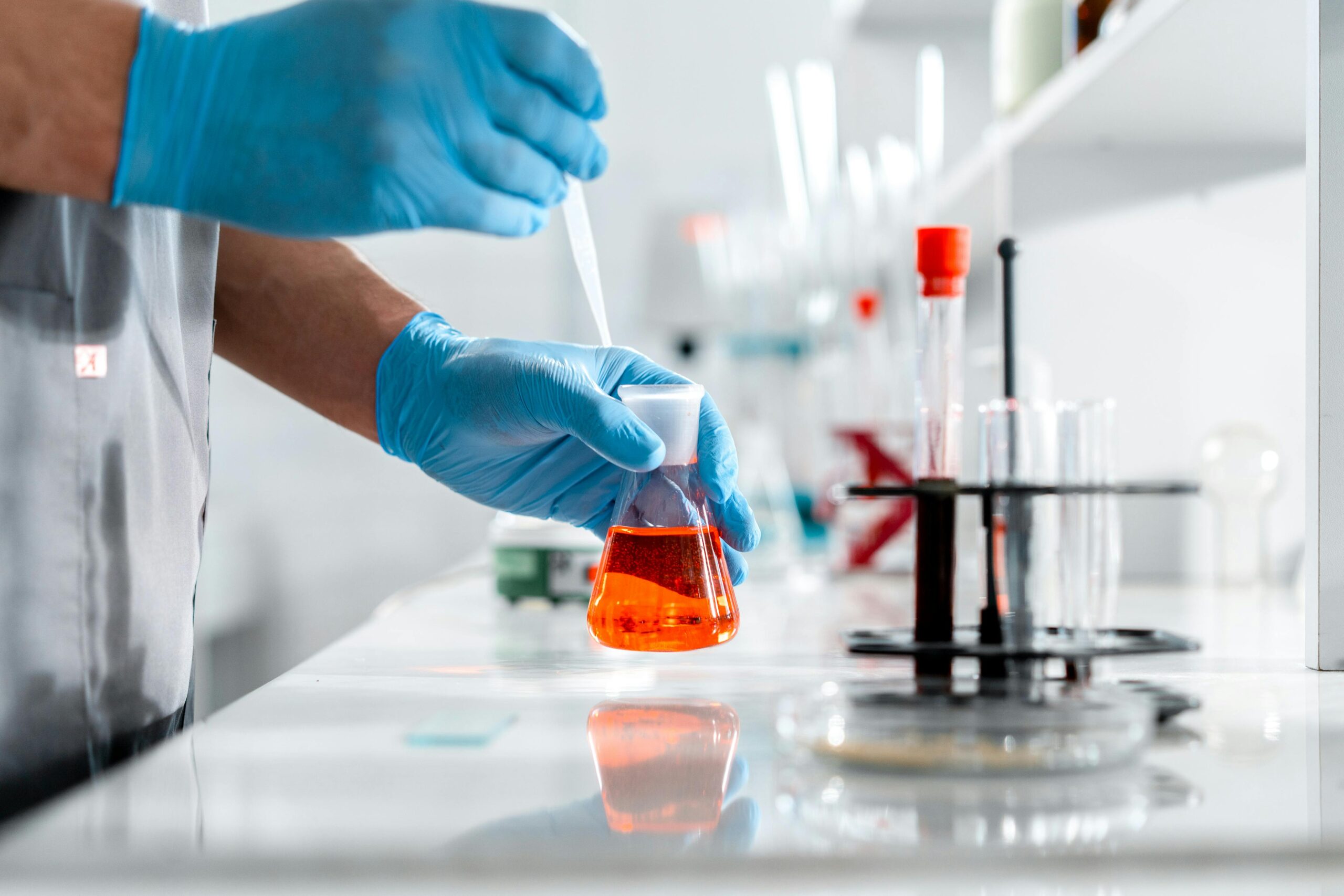Scientist carefully working with Erlenmeyer flask and pipette in a laboratory setting.